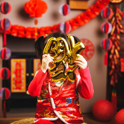 Young girl holding traditional chinese greeting card fu means luck at home