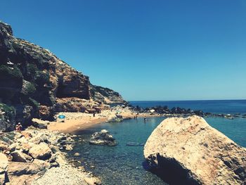 Scenic view of sea and mountains against clear blue sky