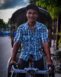 Portrait of man smiling while riding pedicab on road