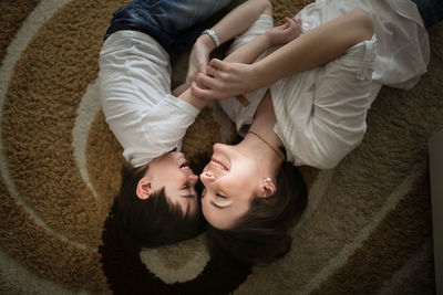 Beautiful brunette mom kisses and hugs with her son on the floor in a home-like normal real interior