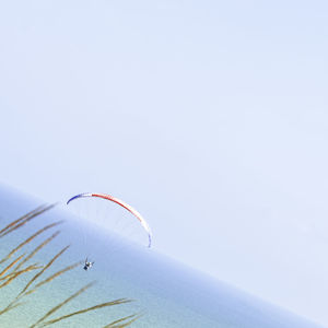 Low angle view of person paragliding against clear sky