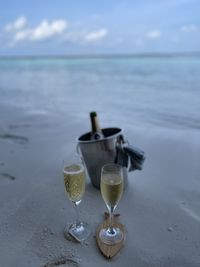 Wineglass on table at beach against sky