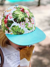 High angle view of girl wearing cap eating ice cream cone while standing outdoors