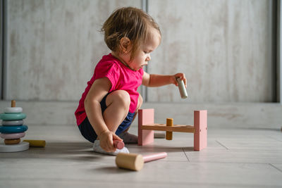 Side view of boy playing with toy on hardwood floor