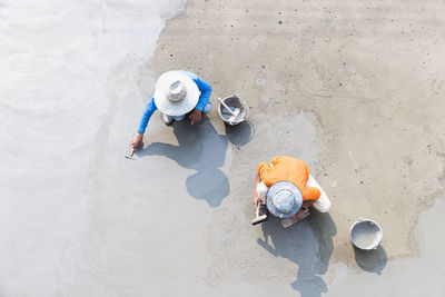 Directly above shot of workers leveling cement on footpath