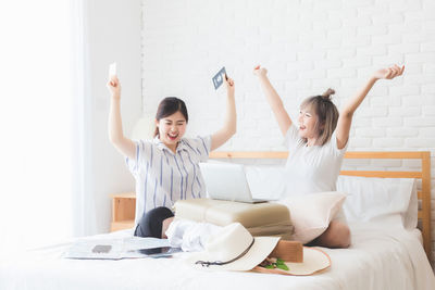 Young woman with arms raised while standing against wall