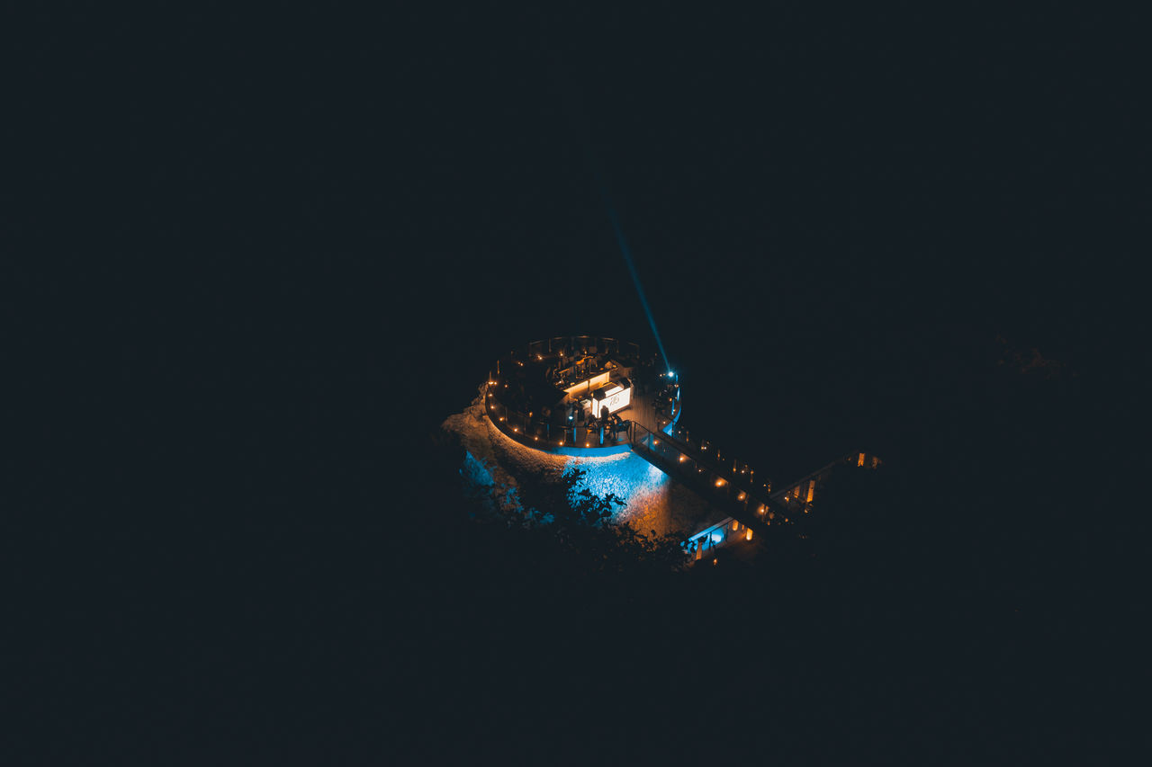 MAN SWIMMING IN SEA AGAINST ILLUMINATED BACKGROUND