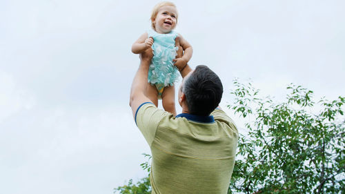 Summer, in the garden, mother, a view from below, the daddy throws his one-year-old daughter, plays