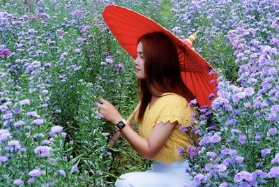 Beautiful woman with pink flowers against plants