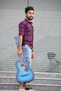 Portrait of young man standing against wall