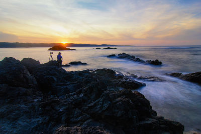 Silhouette of woman standing on beach against sky during sunset