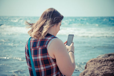 Woman using mobile phone at beach
