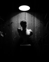 Full length of shirtless man standing against illuminated wall
