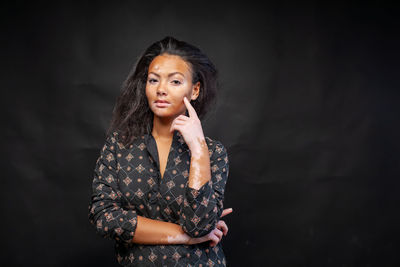 Young woman standing against black background