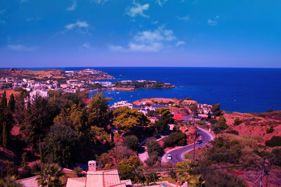 Scenic view of townscape by sea against blue sky