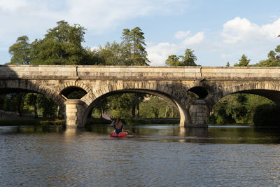 Arch bridge over river against sky