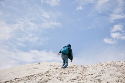 Low angle view of man climbing mountain against sky