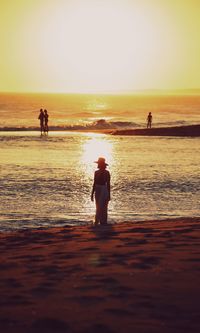 Silhouette people on beach against sky during sunset