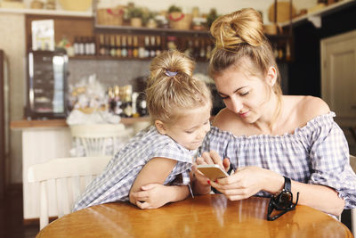 Daughter looking at mother using phone