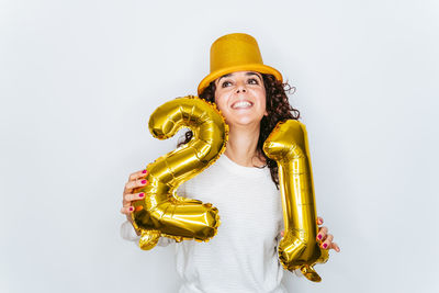 Smiling woman wearing hat holding balloons against white backgrounds