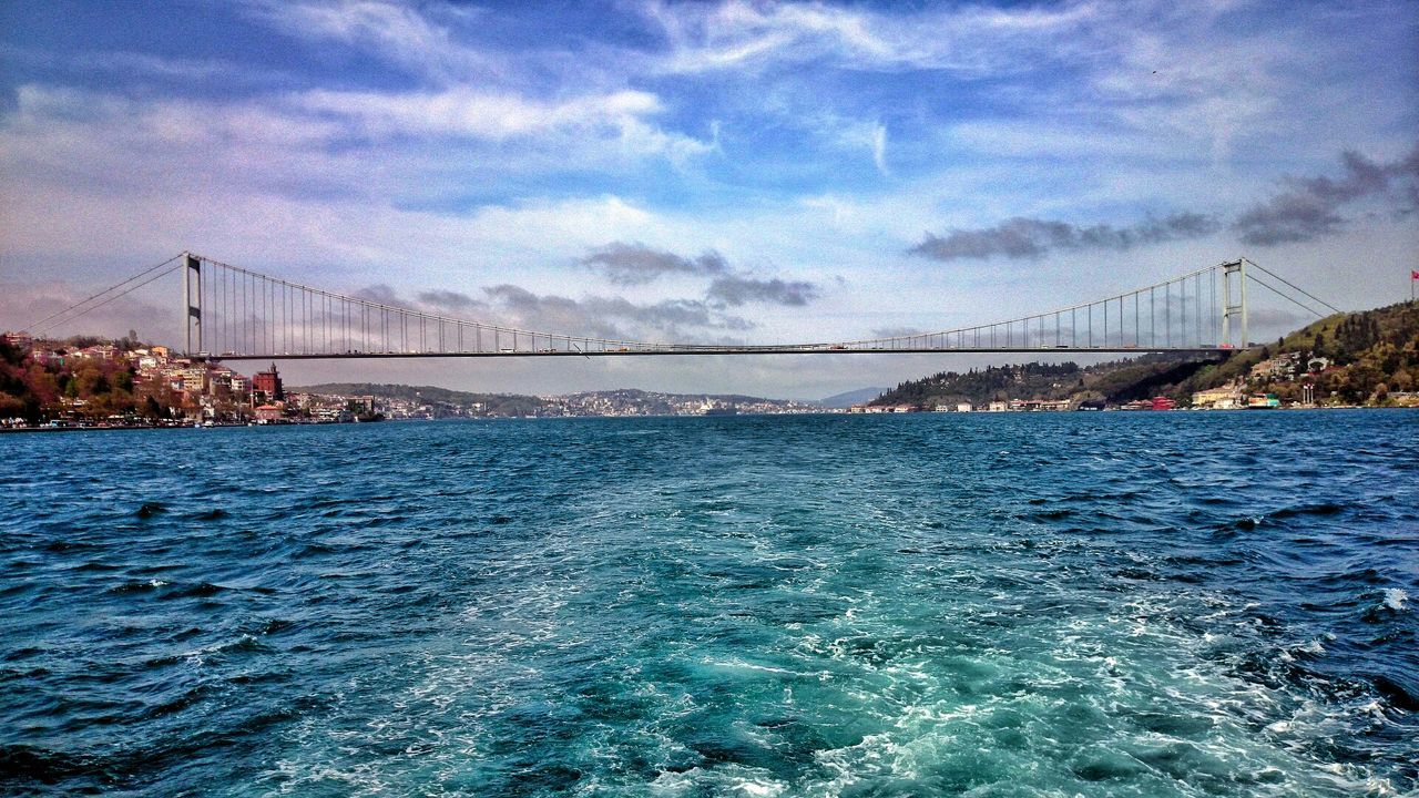 connection, water, bridge - man made structure, built structure, sky, suspension bridge, waterfront, architecture, sea, engineering, transportation, cloud - sky, bridge, river, rippled, travel destinations, cloud, blue, travel, scenics