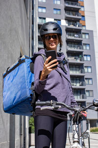 Portrait of young delivery woman using phone