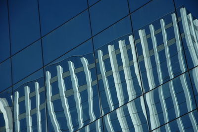 Low angle view of modern glass building in city against sky