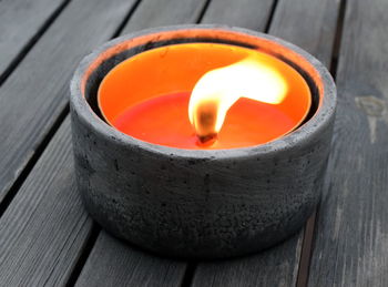 Close-up of lit candle on wooden garden table