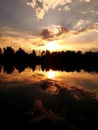 Reflection of trees in water at sunset
