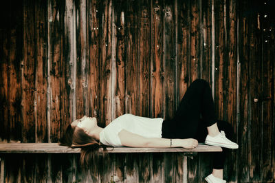 Side view of woman lying on a bench