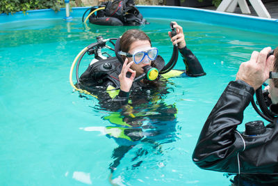 Woman with friend practicing scuba diving in swimming pool