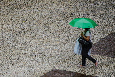 Rear view of woman walking with umbrella