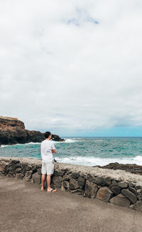 Rear view of woman walking at beach against sky