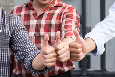 Close-up of men gesturing thumbs up sign