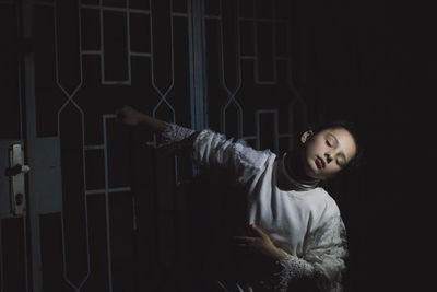 Full length of a girl standing against dark background