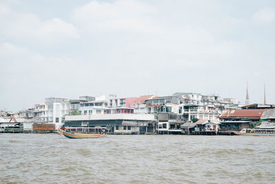 Sea by buildings against sky in city