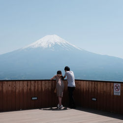 Rear view of couple standing on mountain against sky