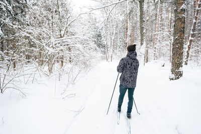 Rear view of man walking on snow covered field