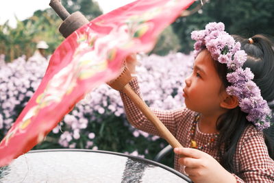 Childen with red umbrellas with flowers farm background