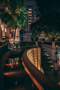 Illuminated building by trees at night