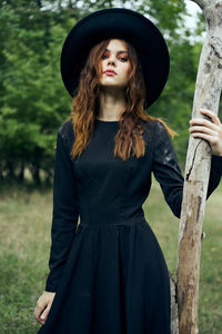 Portrait of young woman standing against trees