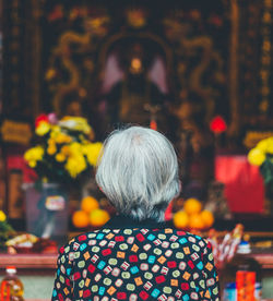 Rear view of woman praying in temple