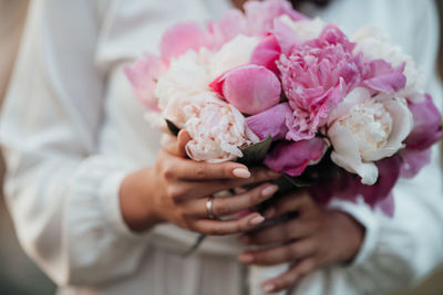 Midsection of woman holding pink rose bouquet