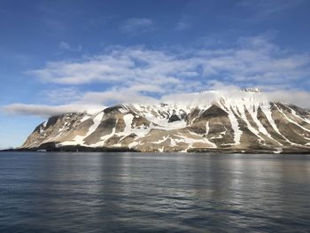 Scenic view of sea and snowcapped mountains against sky