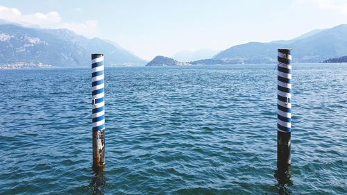 Wooden posts in lake against sky