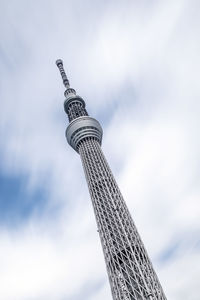 Low angle view of communications tower against cloudy sky