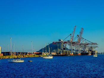 Sailboats in sea against blue sky