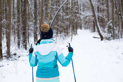 Rear view of woman skiing on snow covered field