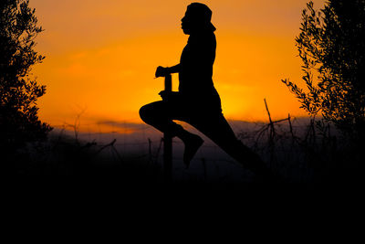 Silhouette man on field against sky during sunset