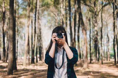 Young woman photographing in forest